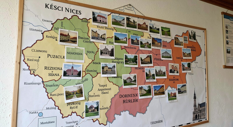 A wall map of Czech regions with small old postcards pinned over several towns.